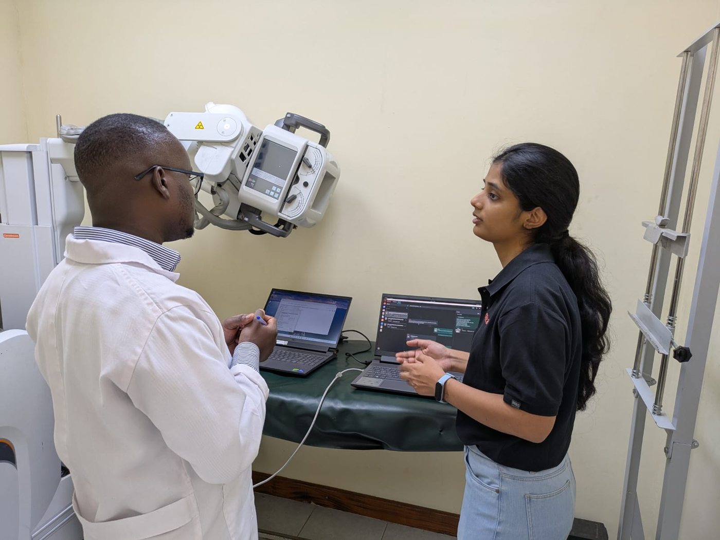 Harshita at a site in Kenya, walking a partner through the qTrack setup next to the X-ray machine